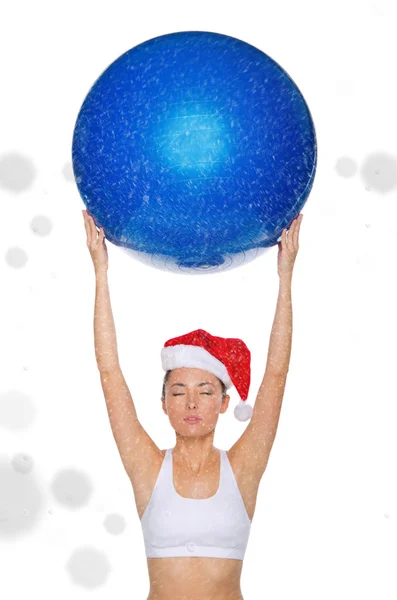 Asian woman in Santa cap holds fitball under snow — Stock Photo, Image