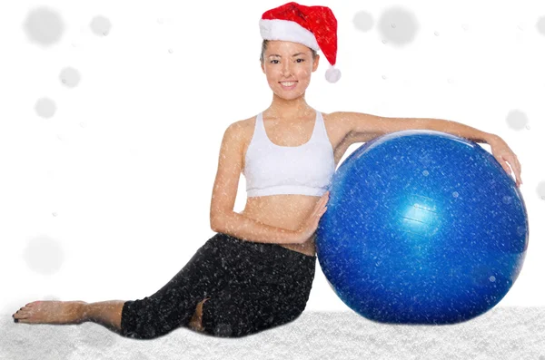 Glückliche asiatische Frau in Weihnachtsmütze mit Fitball unter Schnee — Stockfoto