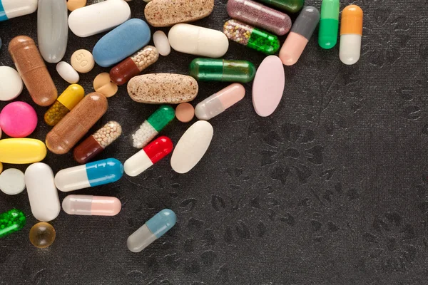Pílulas coloridas em preto — Fotografia de Stock