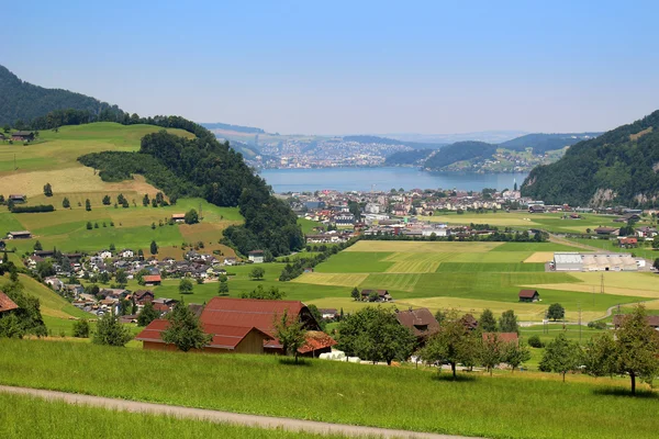 Alpes panorâmicos pastagens, cidades, lago e montanhas — Fotografia de Stock