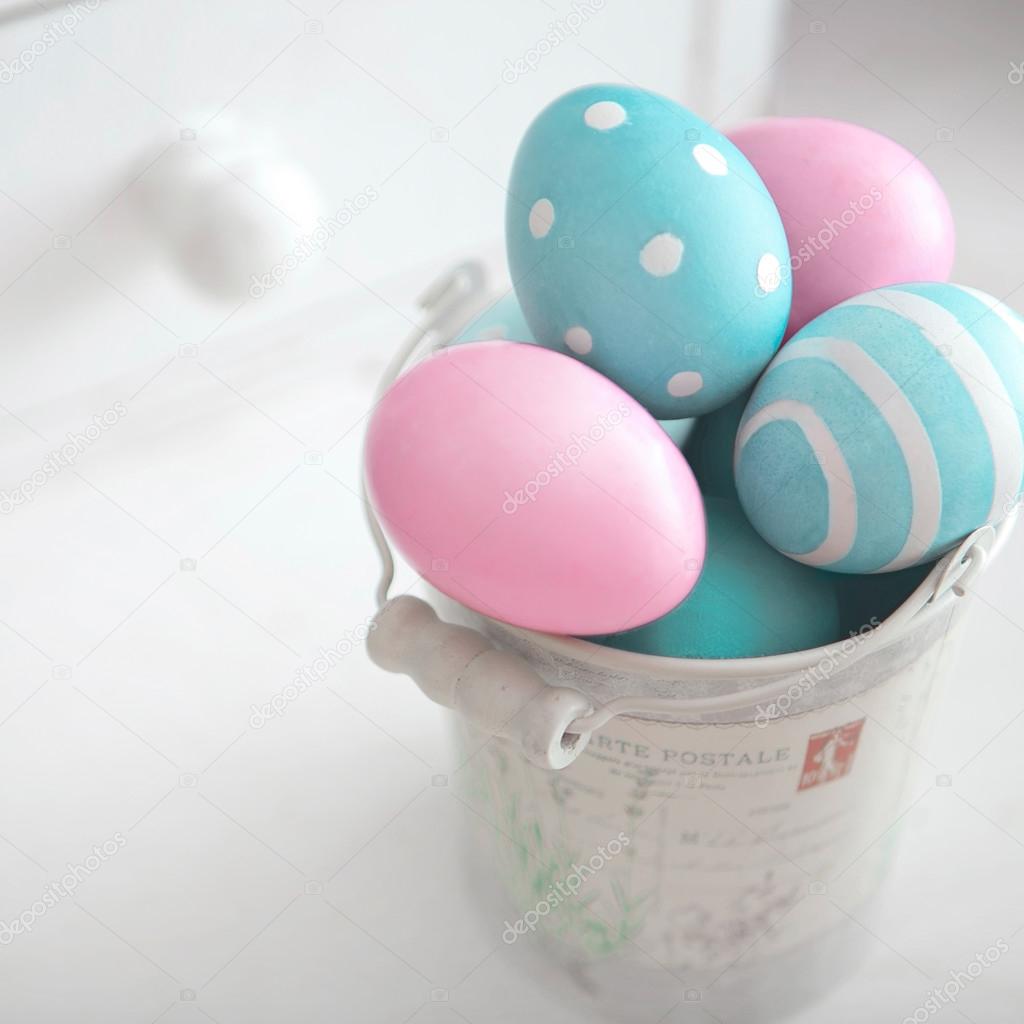 Easter eggs of pastel colors in vintage bucket on light background