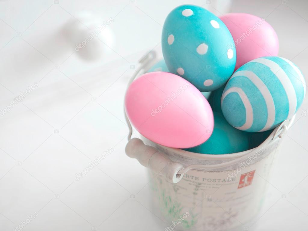 Easter eggs of pastel colors in vintage bucket on light background