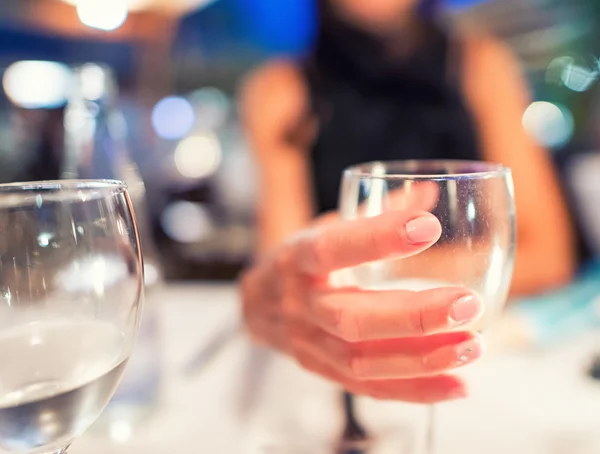 Mulher mão segurando copo de vinho no restaurante — Fotografia de Stock