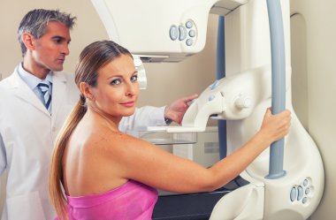 Doktor mamogram çekilen hastaya yardım ediyor.