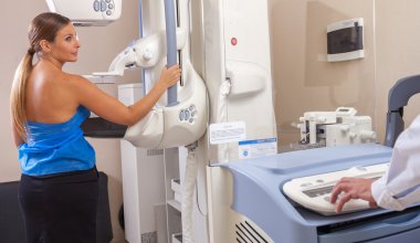 Doctor Assisting Patient Undergoing Mammogram clipart