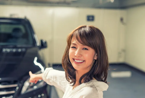 Jovem mulher mostrando carro novo — Fotografia de Stock