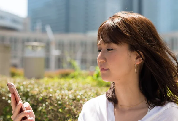 Молодая женщина смотрит в смартфон — стоковое фото
