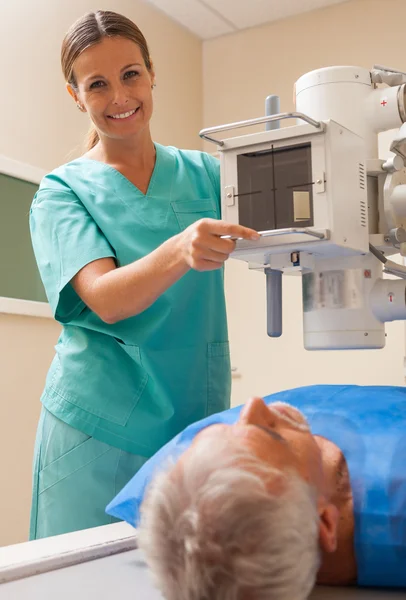Ώριμο αρσενικό ασθενών που υποβάλλονται σε δοκιμή σε ακτινολογικό μηχάνημα που επικουρείται από — Φωτογραφία Αρχείου