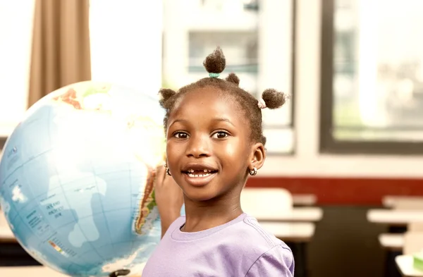 Menina afro-americana na escola primária com terra globo learnin — Fotografia de Stock