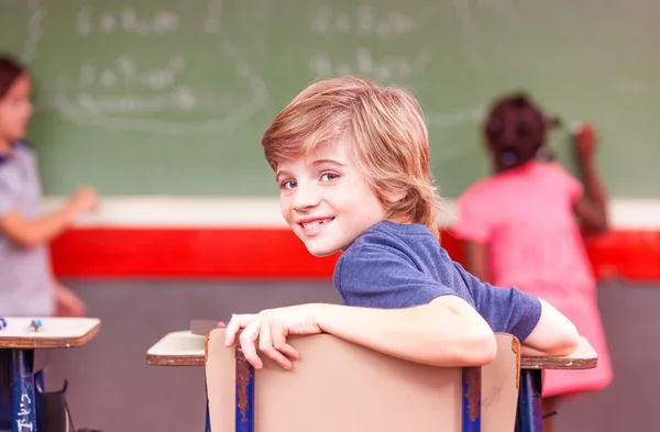 Leende pojke i skolan sitter i klassrummet — Stockfoto