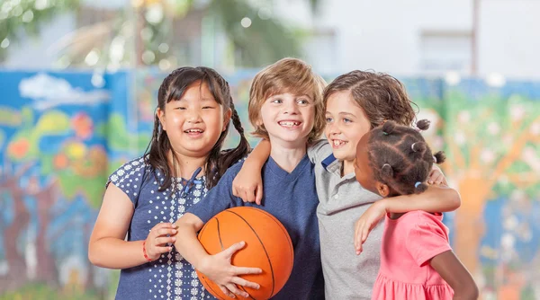 Gruppe von Kindern mit gemischter Rasse spielt Basketball im Schulhof — Stockfoto