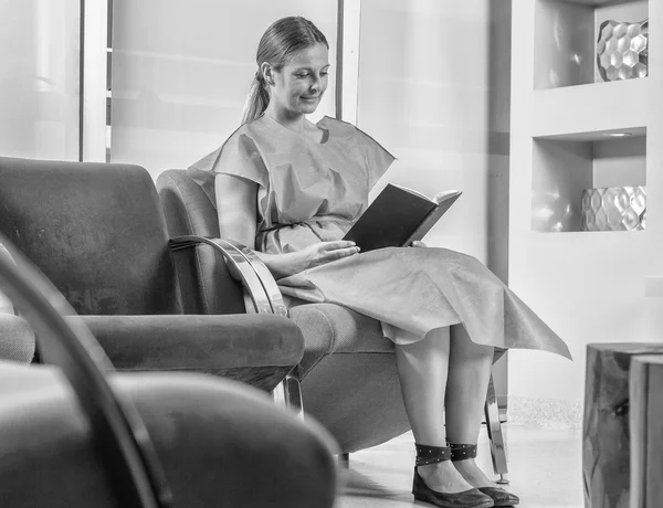 Mulher na sala de espera do hospital lendo um livro — Fotografia de Stock