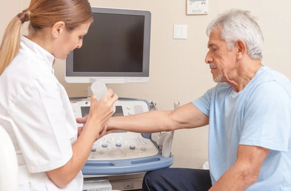 Médico femenino con paciente masculino sometido a ecografía de brazo —  Fotos de Stock