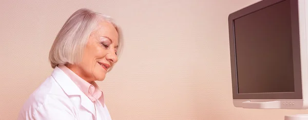 Female doctor in 60s checking technical instruments at clinic — Stock Photo, Image