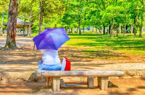 Relaxing seated in the park with water bottle and sun umbrella — Stock Photo, Image