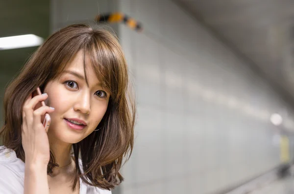 Woman speaking at phone inside subway station — Stock Photo, Image