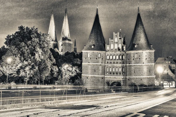 Lübeck, Tyskland. Medeltida stadsporten Holstentor på natten med bil ligh — Stockfoto