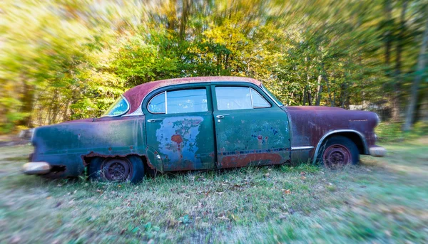 Carro abandonado enferrujando em um campo — Fotografia de Stock