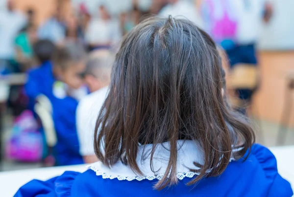 Back view of elementary schoolgirl in her classroom — Stock Photo, Image