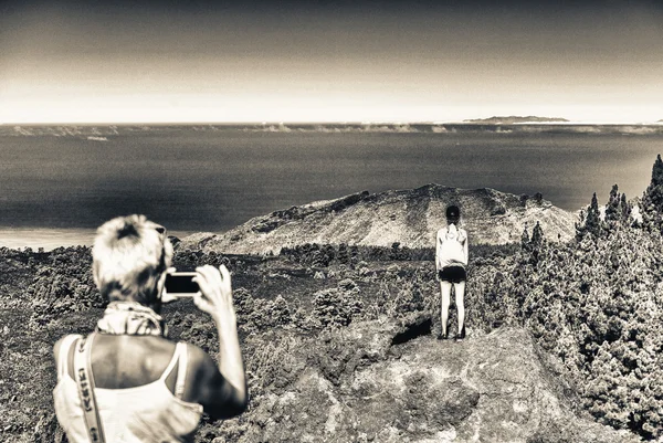 Back view of mother taking a picture of daughter on a mountain s — Stock Photo, Image