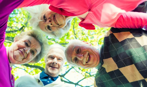 Four elder people looking down to camera relaxing happy outdoor