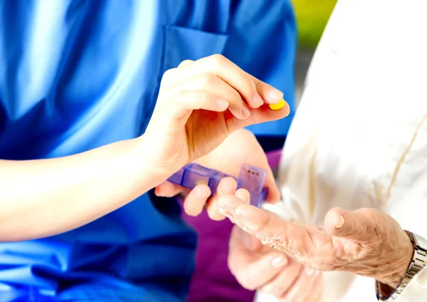 Sjuksköterskan ger piller till äldre människor, händer detalj — Stockfoto