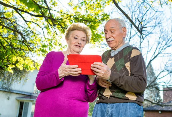 Gelukkige ouderling paar in 70s buiten met technologie-gadget — Stockfoto