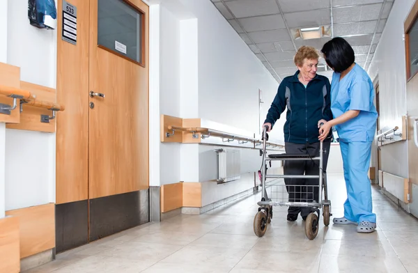 Äldste pensionerad kvinna biträdd av sjuksköterska i rehab anläggning — Stockfoto