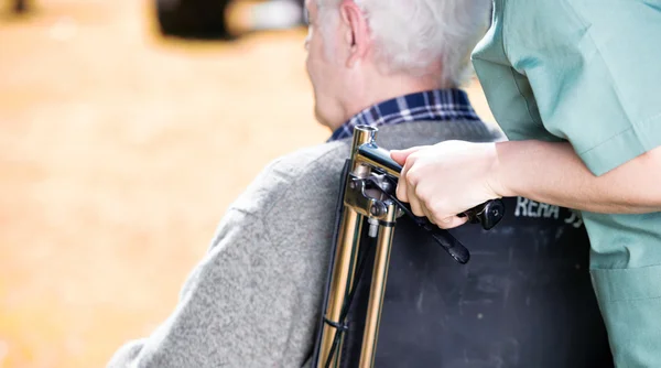 Starší lidé s invalidní vozík pomáhá sestra venkovní — Stock fotografie