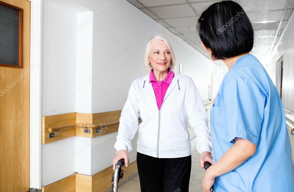 Elder retired woman assisted by nurse in rehab facility