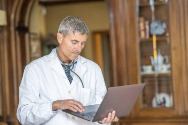 Erkek doktor evdeki bir konferansta dizüstü bilgisayarını kullanıyor..