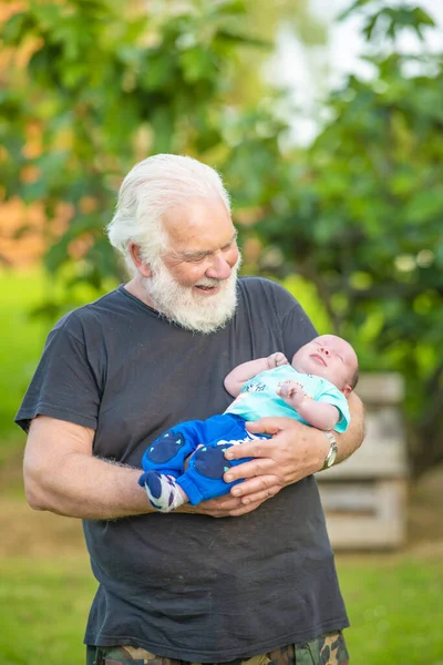 Starší Občan Drží Novorozeně Dítě Náručí Venku — Stock fotografie