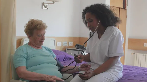 Afrikalı Kadın Doktor Hastanede Yaşlı Bir Kadına Baskı Uyguluyor Yavaş — Stok fotoğraf