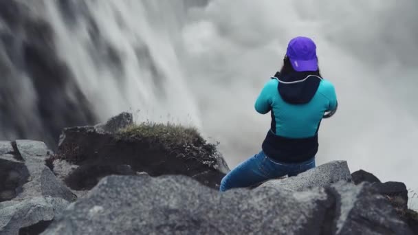Kvinnlig fotograf tar bilder av kraftfulla vattenfall på Island — Stockvideo