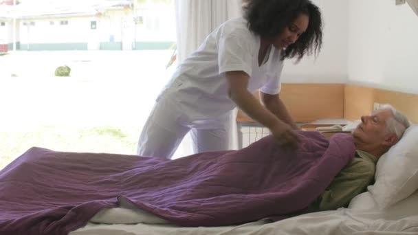 Médica africana ajudando paciente idoso do sexo masculino indo para a cama no hospital. Movimento lento — Vídeo de Stock