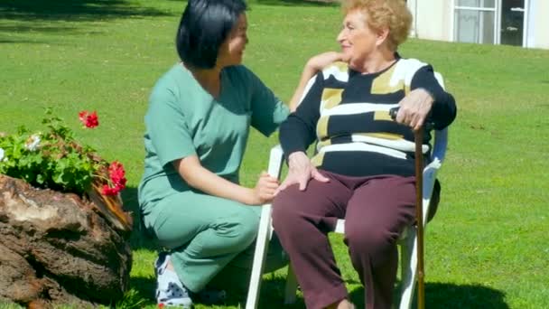 Медсестра помогает пожилой женщине в больничном саду — стоковое видео