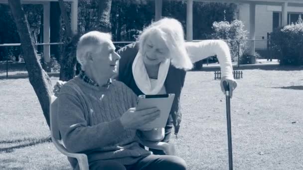 Couple âgé utilisant une tablette dans le jardin. Scène monochome — Video