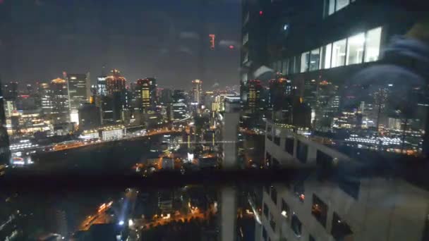 Osaka horizon nocturne à partir du mouvement vers le bas ascenseur externe. gratte-ciel de la ville à travers le verre — Video