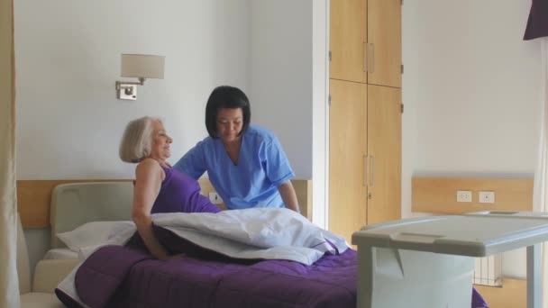 Langzame beweging van Aziatische vrouwelijke arts helpen oudere vrouw opstaan uit bed in het ziekenhuis — Stockvideo