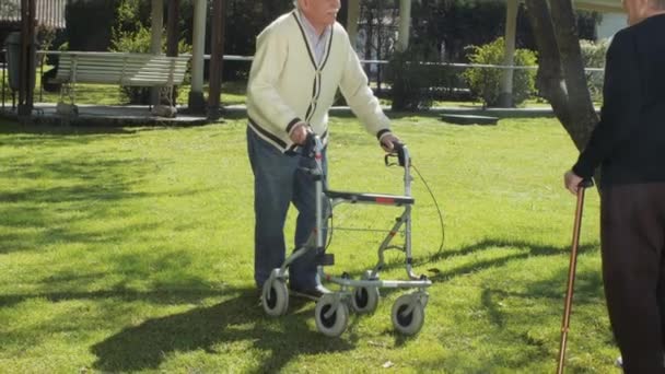 Rallentatore di anziani in pensione coppia all'aperto nel giardino dell'ospedale di riabilitazione con walker e medico. Felicità, riabilitazione e pensionamento — Video Stock