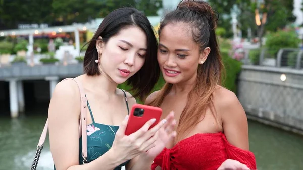 アジア系の女の子のカップルがスマートフォンで何かを見て — ストック写真