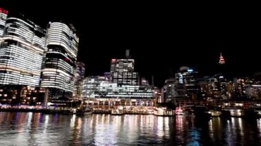 Hareket halindeki bir tekneden Barangaroo Gökdelenleri 'nin gece görüşü, Sydney. Yavaş çekim