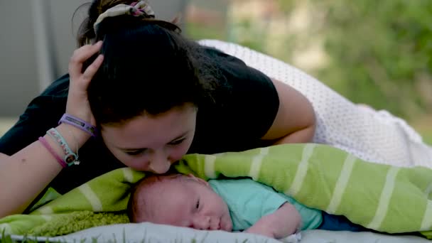 Jong meisje zoenen haar pasgeboren broer in de stad park — Stockvideo