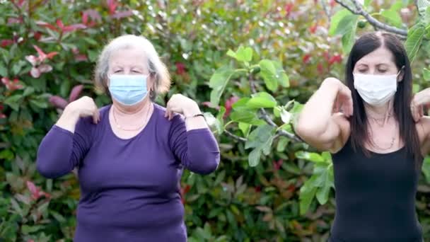 Четыре женщины тренируются в саду в масках. Тренировки на открытом воздухе во время вспышки коронавируса. Здоровая женщина, замедленная съемка — стоковое видео