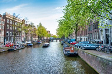 AMSTERDAM, NETHERLANDS - 25 NİSAN 2015: Kanalda tekneli geleneksel evler ve binalar.