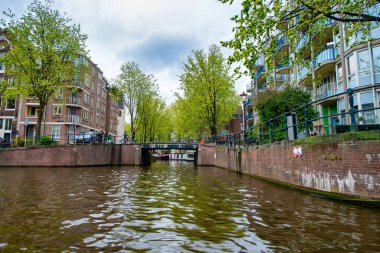 AMSTERDAM, NETHERLANDS - 25 Nisan 2015: Kanal üzerindeki geleneksel evler ve binalar.