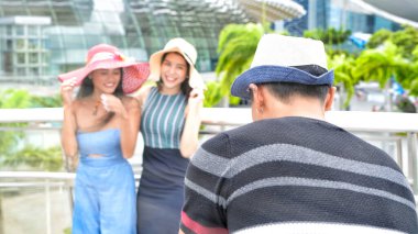 Üç Asyalı genç arkadaş şehir sokaklarında fotoğraf çekerek dışarıda vakit geçirmeyi seviyor..