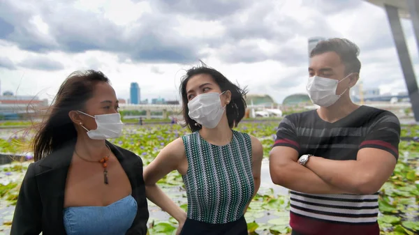 三个亚洲的年轻朋友站在城市的室外 带着口罩 在眼镜蛇的大流行中说话 — 图库照片