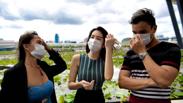 三个亚洲的年轻朋友站在城市的室外 带着口罩 在眼镜蛇的大流行中说话 — 图库照片