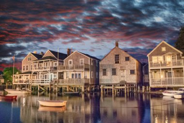 Wooden homes over the ocean. Water reflections at sunset. clipart
